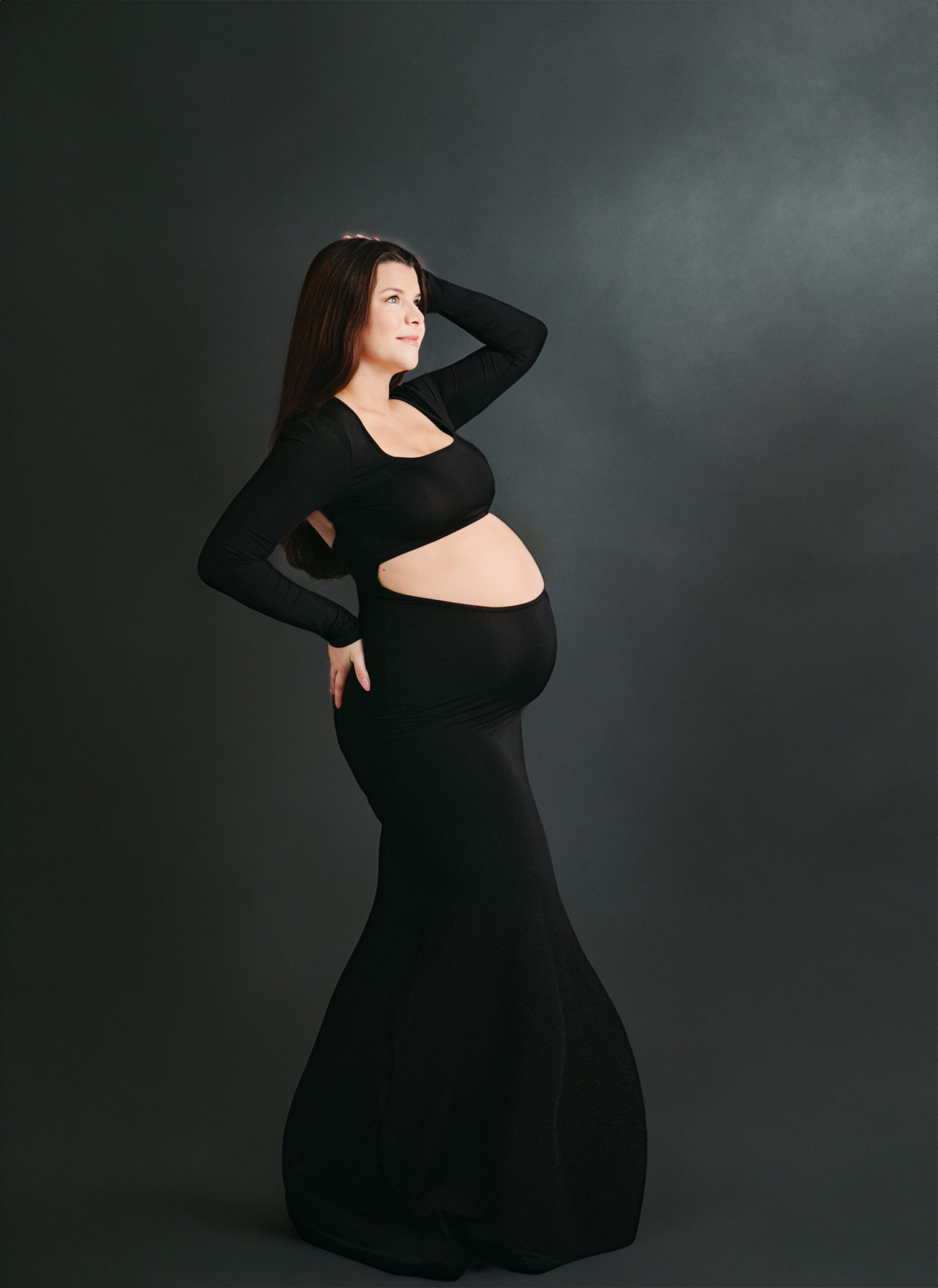 Studio portrait of an expectant mother wearing an elegant gown, showcasing her pregnancy glow