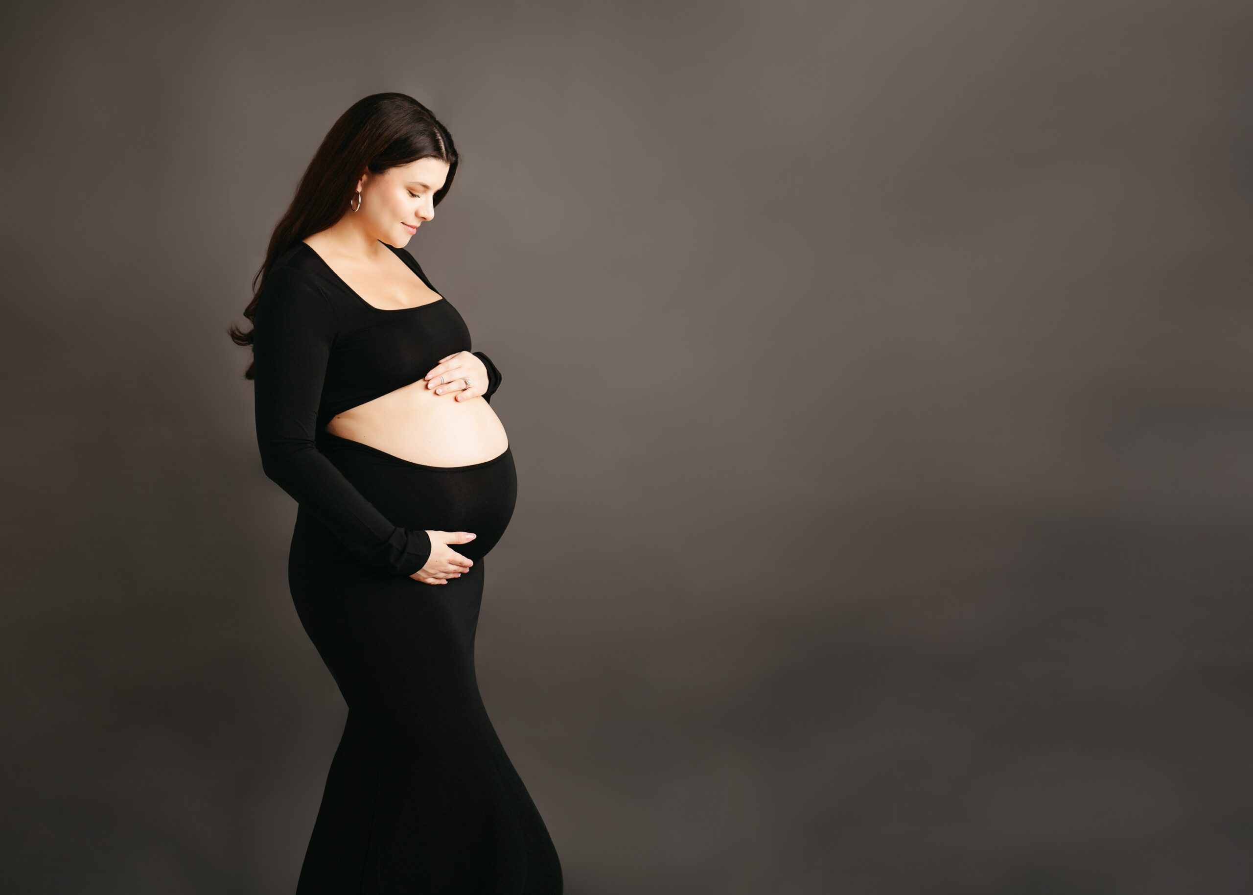 Studio portrait of an expectant mother wearing an elegant gown, showcasing her pregnancy glow